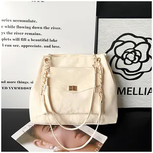 Détail d'un sac bandoulière crème avec texture pierre, fermoir rotatif et chaîne métal