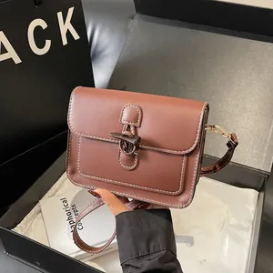Macro view of brown leather square bag with contrast stitching and horn toggle closure