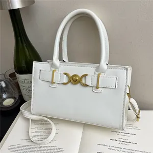 Elegant white leather handbag with golden heart clasp shown on a book with home decor