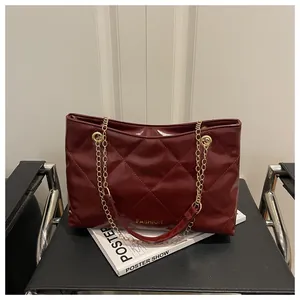 Gros plan d'un sac cabas matelassé rouge bordeaux avec chaîne dorée et logo Fashion sur une chaise