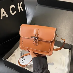 Detail view of brown leather bag with horn buckle and white stitching in gift box