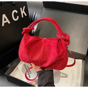 Detail view of red faux suede handbag with knotted handle and elegant pleated texture