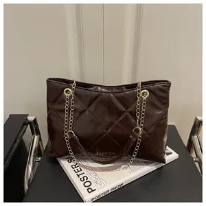 Détail d'un sac cabas matelassé marron foncé avec poignées en chaîne dorée et logo