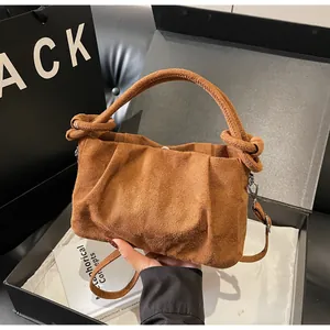 Detail of a brown suede handbag with ruched cloud design and knotted handle details