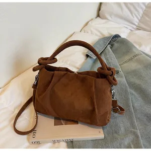 Detailed shot of dark brown vintage suede handbag with knotted handle and adjustable strap