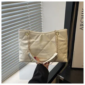 Détail macro du sac cabas beige matelassé avec logo FASHION doré et bandoulière chaîne