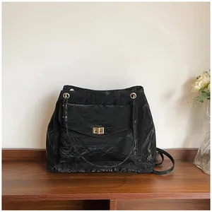 Détail d'un sac à bandoulière noir plissé avec fermoir doré sur un bureau en bois