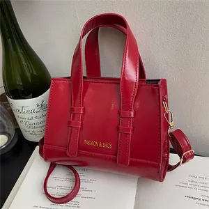 Glossy red vintage square handbag with dual top handles and adjustable shoulder strap