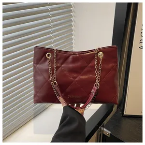 Détail macro du sac cabas matelassé bordeaux avec chaîne dorée et lettrage FASHION