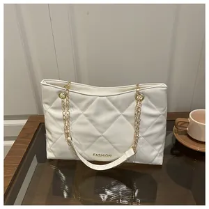Vue détaillée d'un sac cabas blanc matelassé avec des bandoulières en chaîne dorée et texte