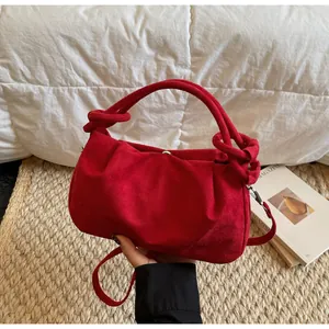 Detail of red faux suede handbag showing knotted handle texture on rustic background