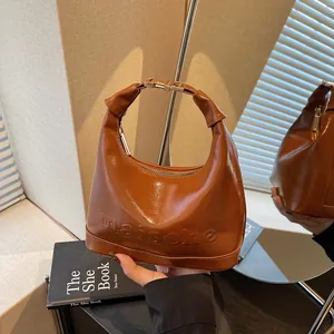 Brown gloss leather bucket bag with embossed logo and elegant gold metal buckle