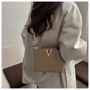 Sac seau kaki avec logo V doré et détails de texture portés par un mannequin