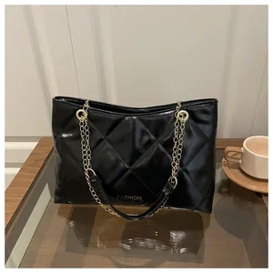 Détail du sac cabas matelassé noir avec chaîne dorée et texture cuir brillante