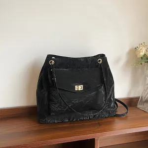 Sac fourre-tout noir plissé chic avec fermoir doré sur un banc en bois foncé