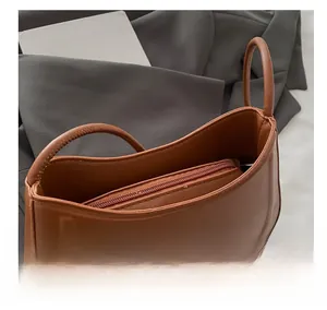 Close-up of brown leather shoulder bag with metallic bow detail and zip closure