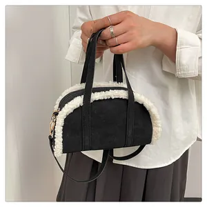 Détail du sac à main en daim noir avec bordure en fourrure blanche et boucles dorées