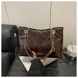 Détail d'un sac cabas marron foncé matelassé avec chaîne dorée et lettrage FASHION