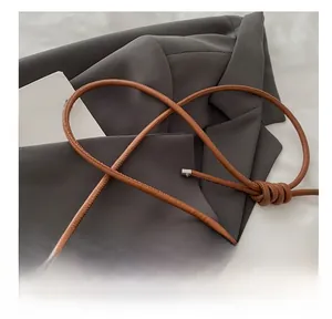 Detail of a brown leather shoulder bag featuring unique knotted thin strap design