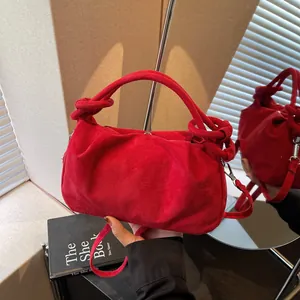Vintage red faux suede handbag with knotted handle detail shown against a mirror