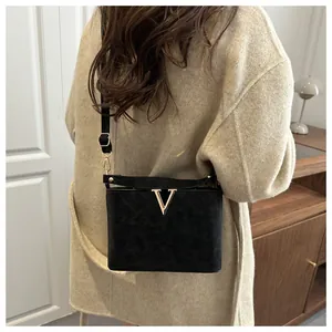 Détail du sac seau noir en daim avec boucle en V dorée et bandoulière réglable