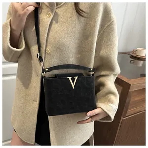 Détail du sac seau noir texturé avec logo métallique en V doré et bandoulière réglable