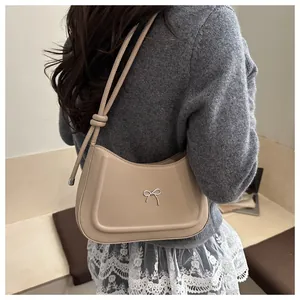 Detail of a beige bow hobo bag with silver metallic knot and elegant knotted shoulder strap