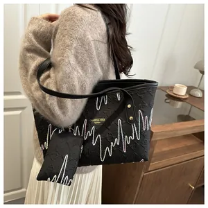 Detail of black tote bag with colorful wave embroidery and matching coin purse charm