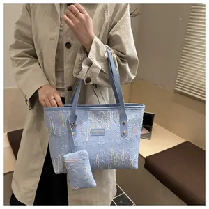 Detail of light blue textured tote bag with wave embroidery and mini coin purse charm