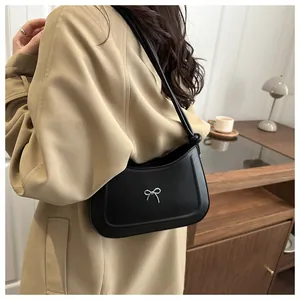 Close-up of elegant silver bow detail on black leather shoulder bag with a stylish knot