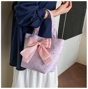 Detail of light purple star-patterned tote bag with a large pink silk bow decoration