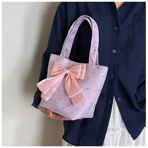 Close-up of lilac tote bag featuring silver stars and a large pink silk bow detail