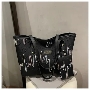 Detail view of black tote bag with colorful zigzag stitching and embossed texture set