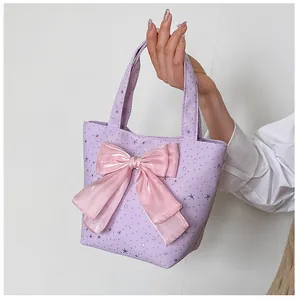 Detail of lavender tote bag featuring a pink bow and silver star patterns with a handle