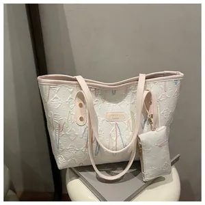 Close-up of white quilted tote bag with colorful wave embroidery and pink handle strap