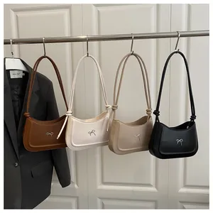 Detail view of four leather shoulder bags with metal bow accent and knotted straps