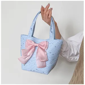 Close-up of light blue sequined star tote bag featuring a large pink silk bow detail