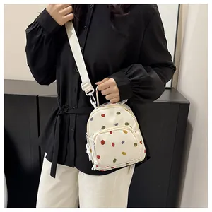 Dettaglio mini zaino con pois colorati e tracolla regolabile in fettuccia bianca