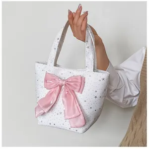 Close-up of a white canvas tote bag featuring silver stars and a pink satin bow detail