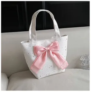 Close-up of white canvas tote bag with silver star prints and a large pink satin bow