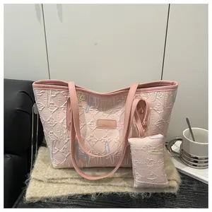Pink quilted tote bag with embroidery details and matching mini pouch on a soft rug