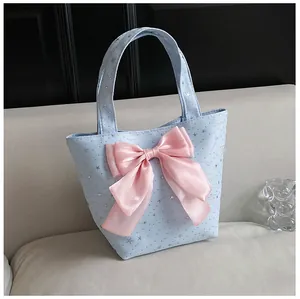Detail of light blue sequin star tote bag featuring a large pink silk bow and soft handle