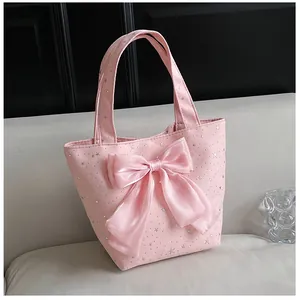 Close-up of pink canvas tote bag with silver star prints and large silk bow on a sofa