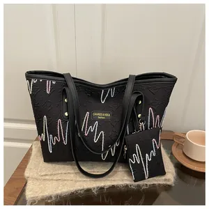 Detail view of black tote bag set with wavy embroidery on knit fabric with coffee cup