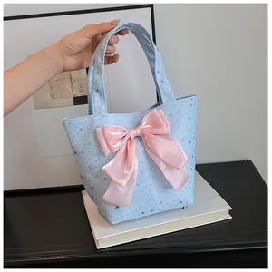 Detail of light blue star sequin tote bag featuring a large pink satin bow decoration