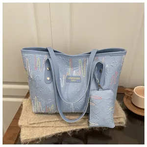 Detail of light blue tote bag with colorful wave embroidery and brand leather patch