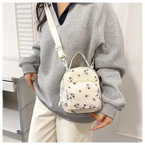 Dettaglio di un piccolo zaino con stampa floreale viola indossato come borsa a tracolla