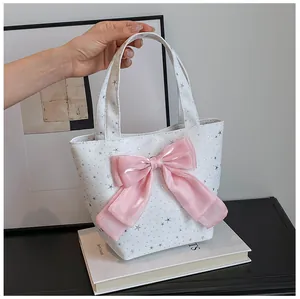Close-up of a white tote bag with silver stars and a large pink satin ribbon bow