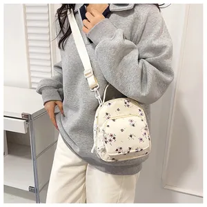Dettaglio di mini zaino con motivo floreale, spalline e tasche con cerniera