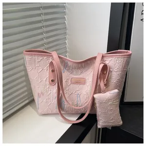 Close-up of pink tote bag with textured letter E embroidery and a small coin purse
